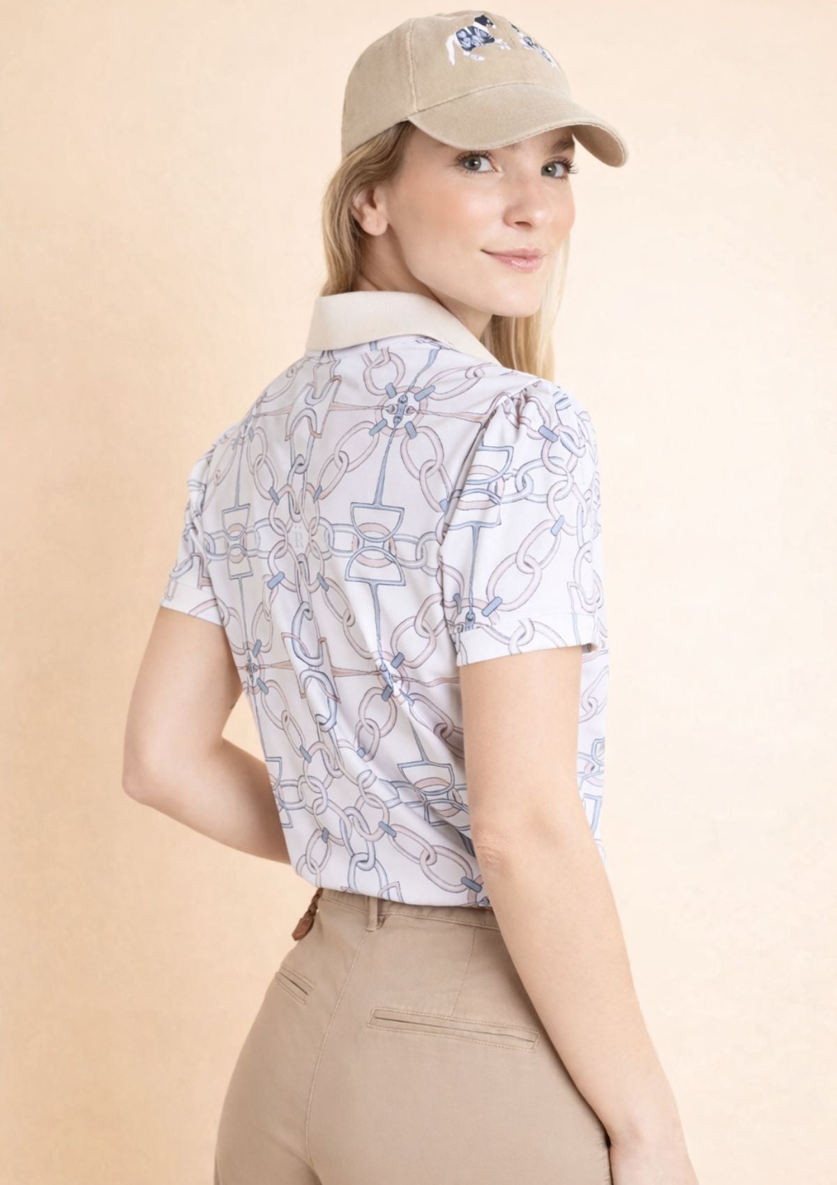 Woman wearing a patterned shirt and cap on a beige background