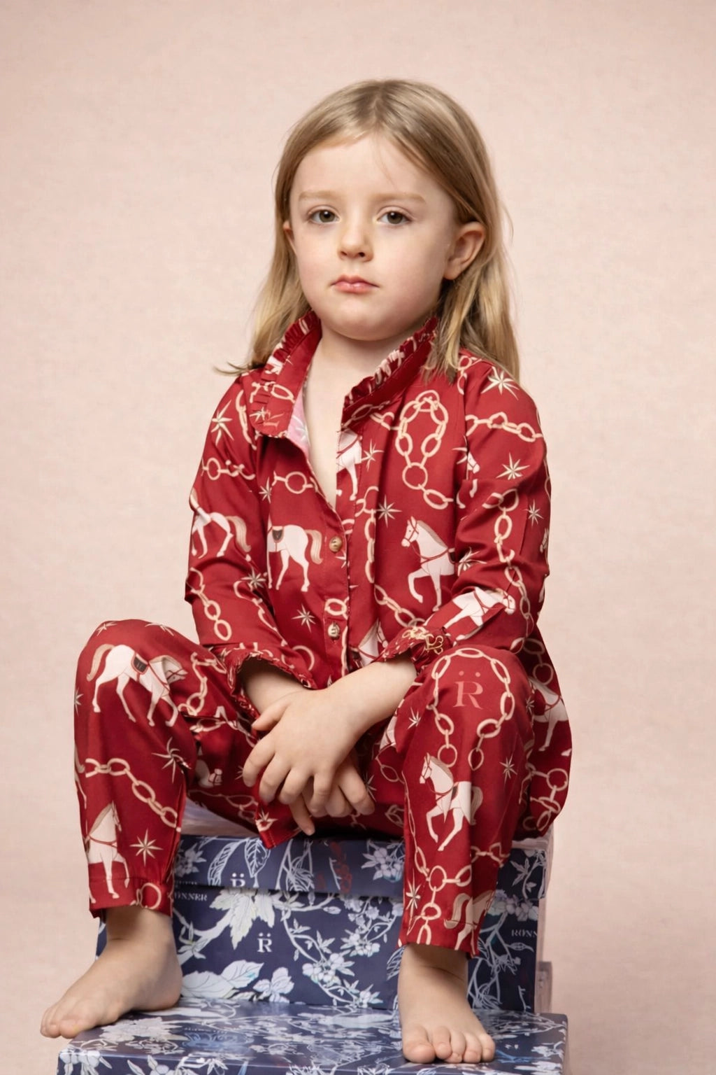 Young girl wearing red pajamas with animal pattern on a pink background