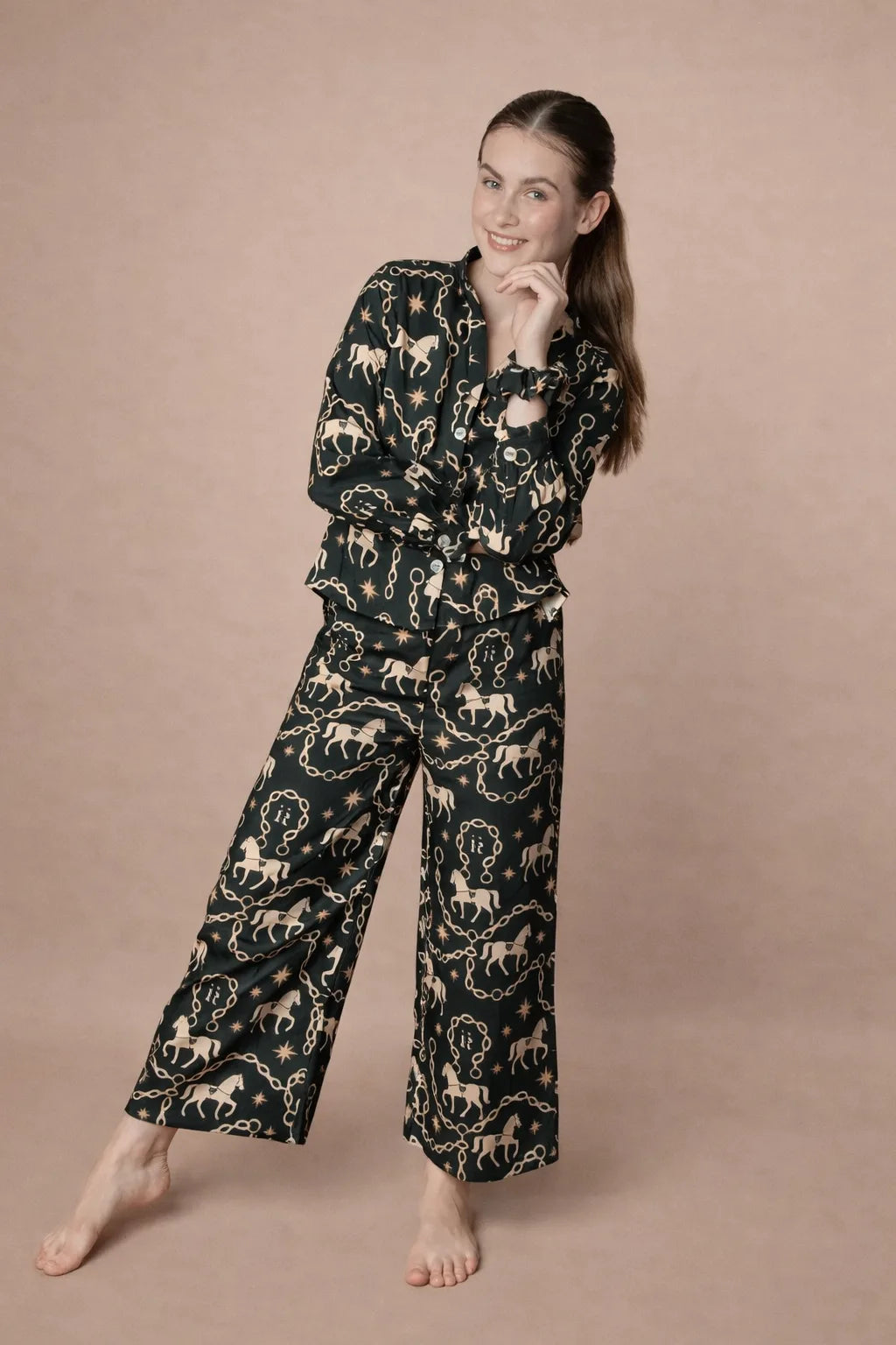 Woman wearing a black pajama set with horse pattern on a beige background